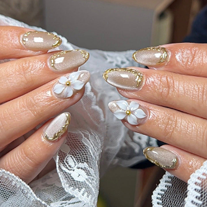 Acrylic nail set with elegant gold embellishments and floral accent Kalsten