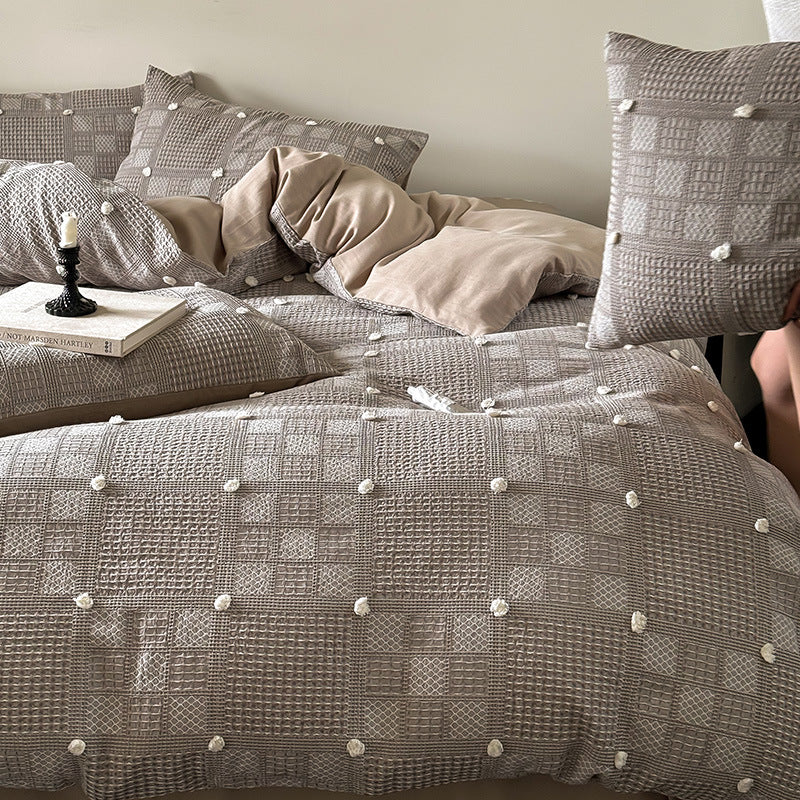 Luxurious cotton bedding set with textured waffle appearance and pompom details