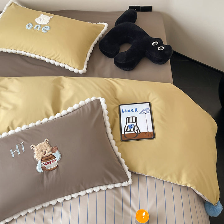 Children's bed set with teddy bear embroidery, pom-pom edging, and reversible blanket