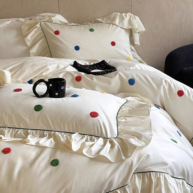 Bedding set with embroidered dots, decorative ruffles, and fine piping