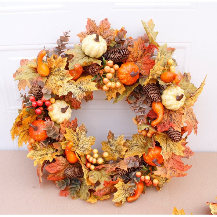 Autumn door wreath with artificial maple leaves, cones, and decorative pumpkins