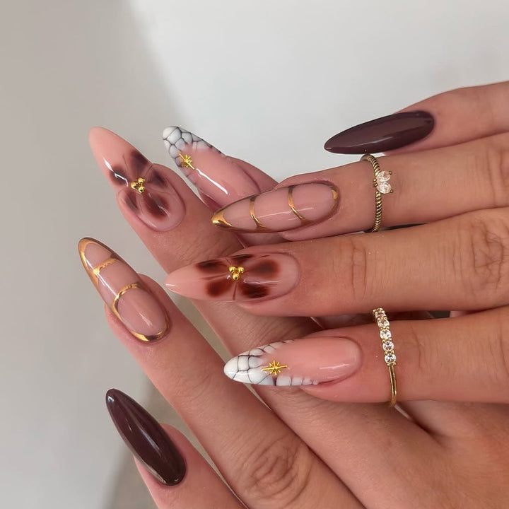 Artful Stiletto nails with gold accents and decorative floral designs Kalsten