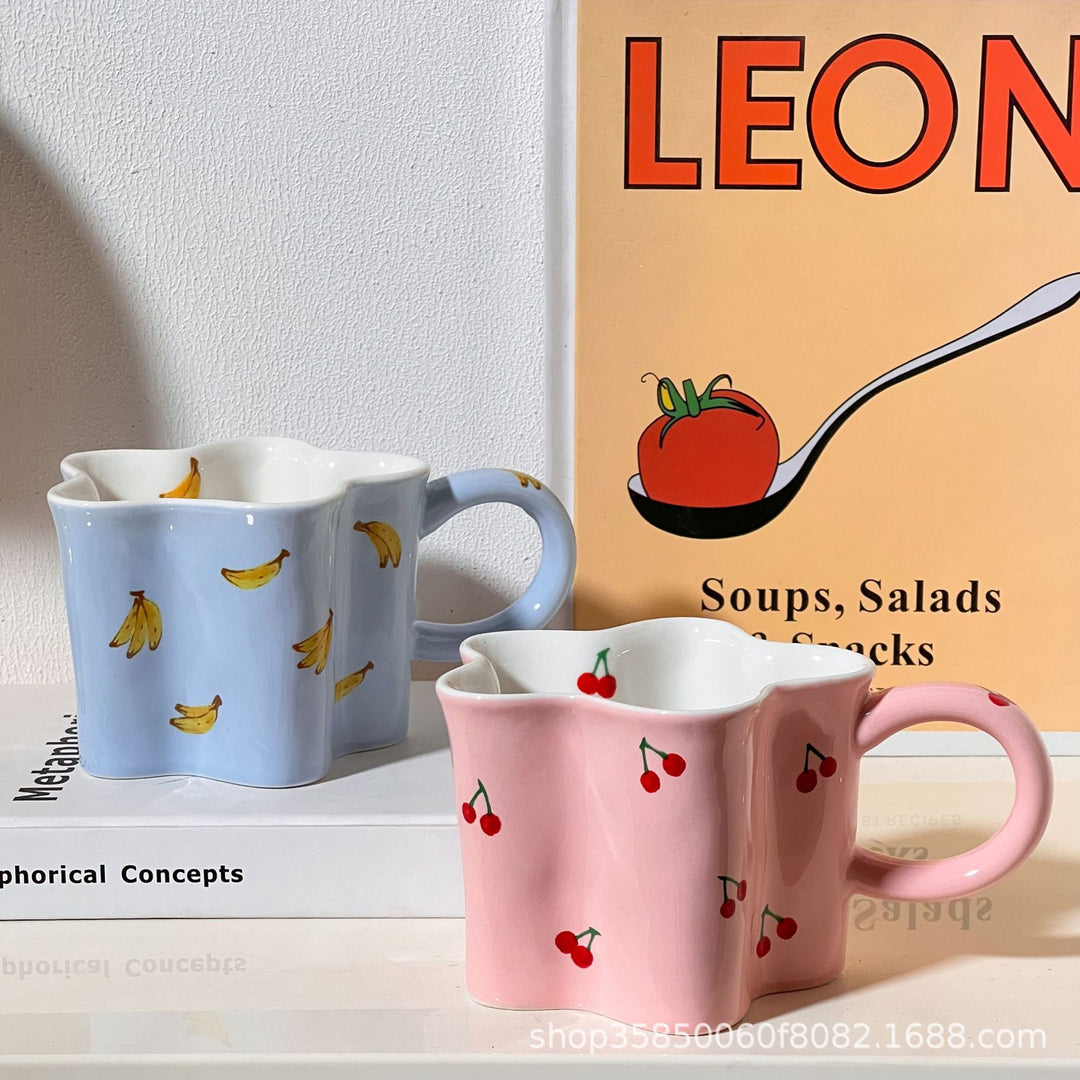 Ceramic coffee mug with flower-shaped wavy rim, illustrative banana decor and ergonomic handle