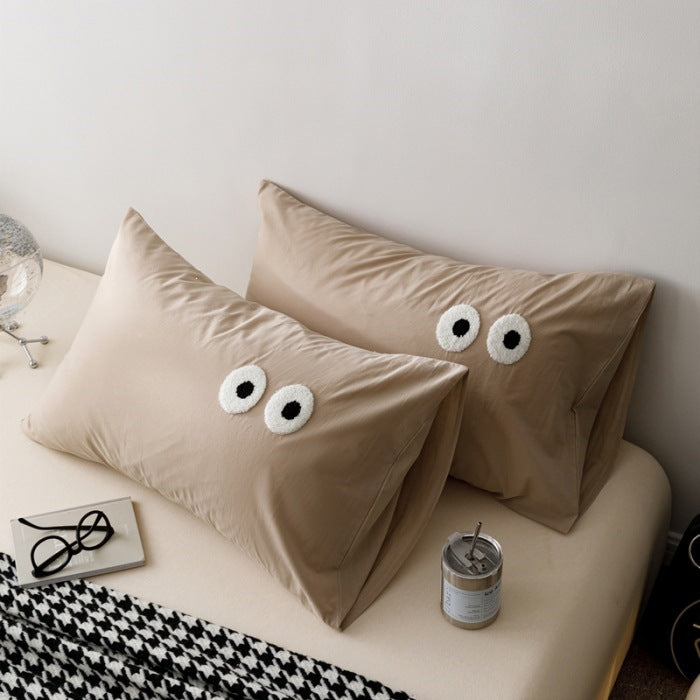 Playful cushion cover set with embroidered eye appliqués made of soft cotton fabric